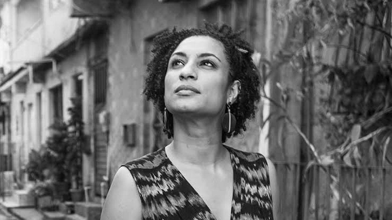 Mulher olhando para o céu com expressão pensativa em ambiente urbano.