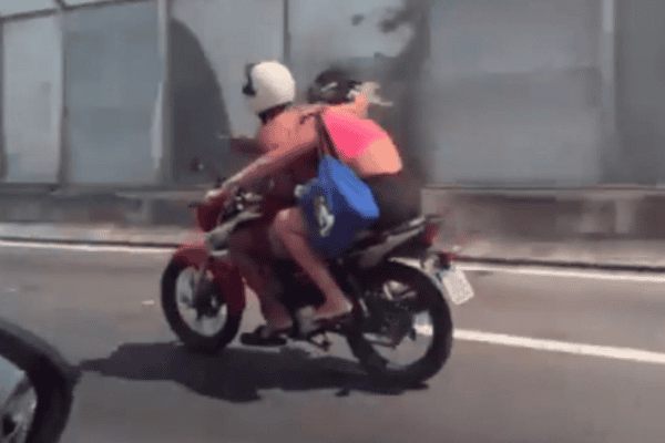 Mulher na garupa assume condução da moto enquanto namorado come marmita tranquilamente