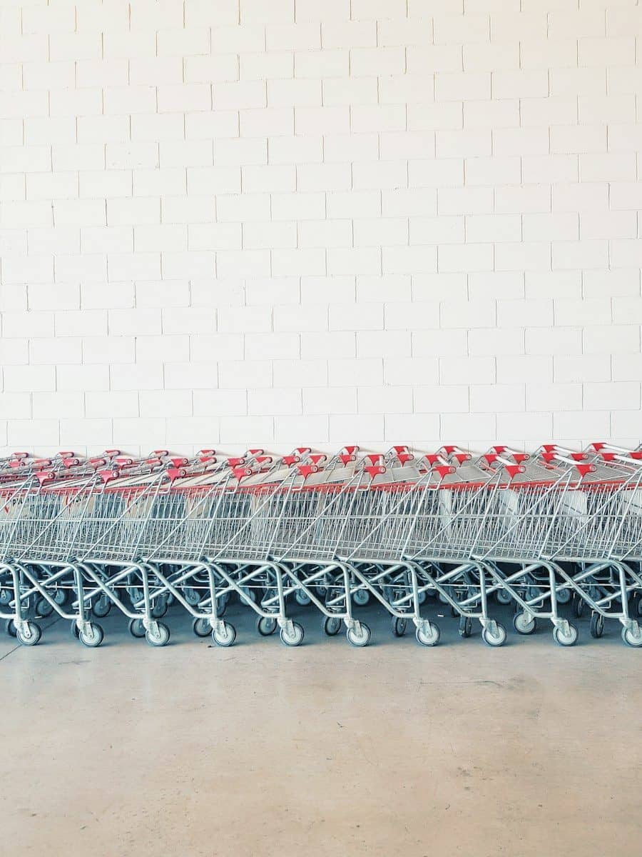 gray-and-red metal shopping cart lot beside wall