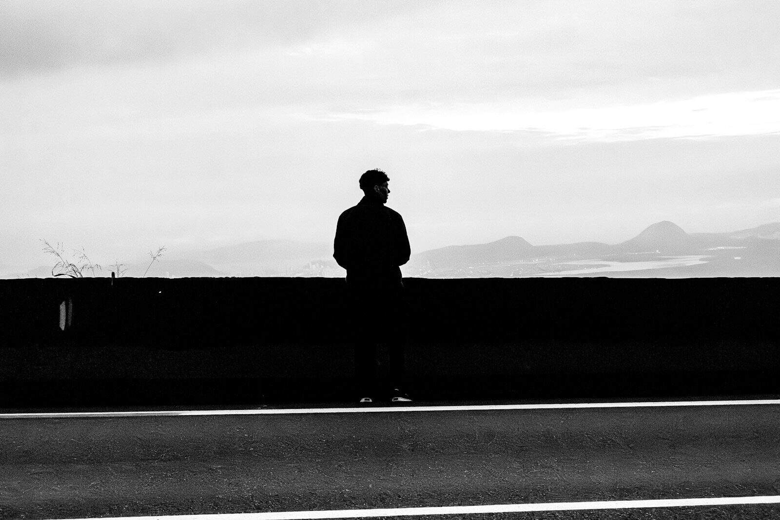 Silhouette of a man standing by a wall